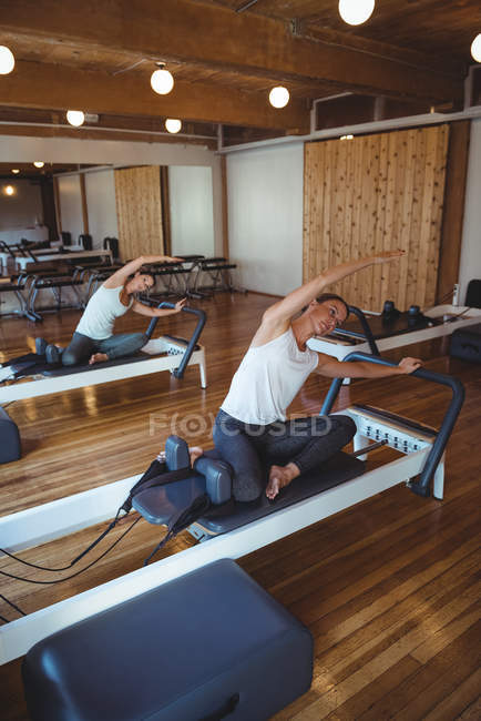 Mujeres practicando pilates en reformadores en gimnasio - foto de stock