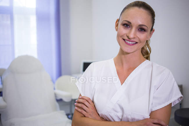 Porträt eines lächelnden Zahnarztes, der mit verschränkten Armen in der Klinik steht — Stockfoto