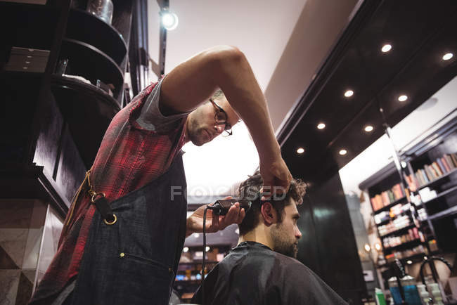 Uomo ottenere capelli tagliati da parrucchiere con trimmer in negozio di barbiere — Foto stock