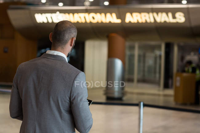 Vue arrière de l'homme d'affaires utilisant une tablette numérique dans la salle d'attente du terminal de l'aéroport — Photo de stock