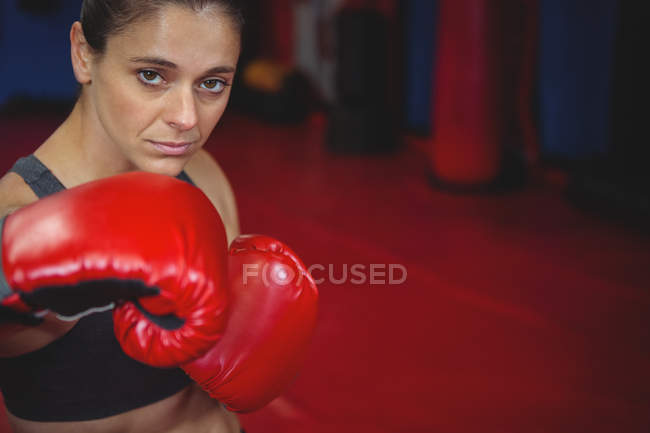 Confident female boxer performing boxing stance in fitness studio — Stock Photo