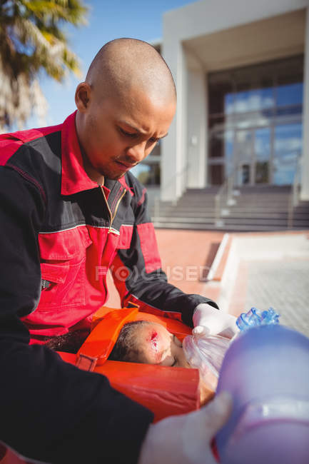 Paramedic giving oxygen to injured girl at accident spot — Stock Photo