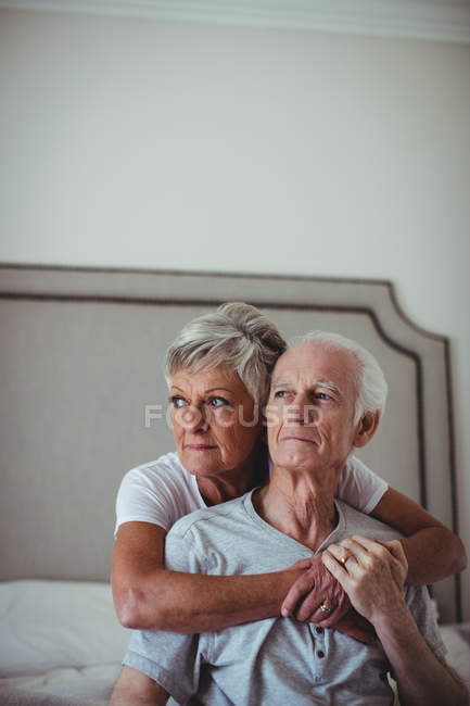 Seniorin umarmt älteren Mann auf Bett im Schlafzimmer — Stockfoto