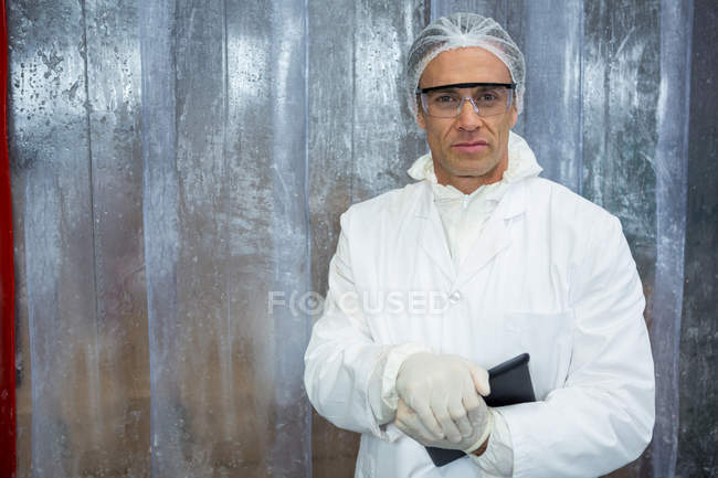 Retrato del técnico que sostiene la tableta digital en la fábrica de carne - foto de stock