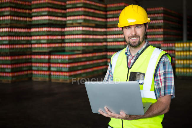 Retrato de un joven trabajador masculino usando un ordenador portátil en el almacén - foto de stock