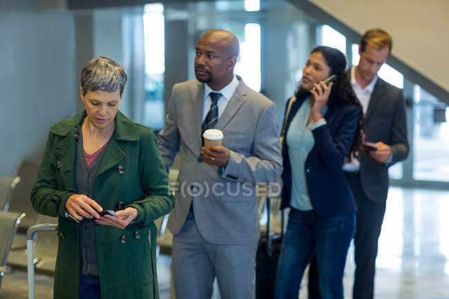 Viajeros de negocios esperando en cola en el aeropuerto - foto de stock