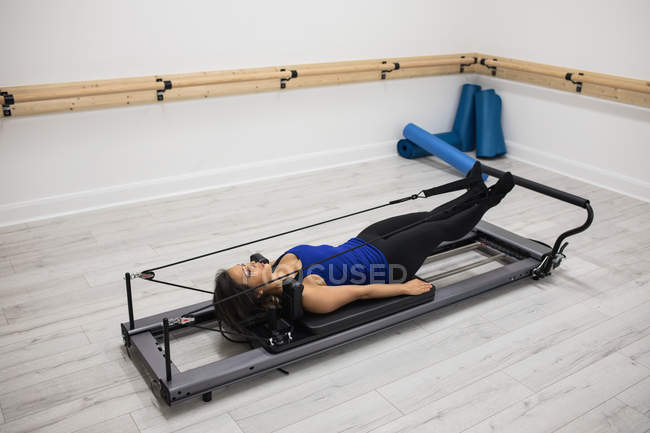 Mid adult woman exercising on reformer in gym — Stock Photo