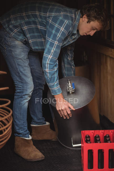 Человек поднимает сусло, чтобы сделать пиво на домашней пивоварне — стоковое фото