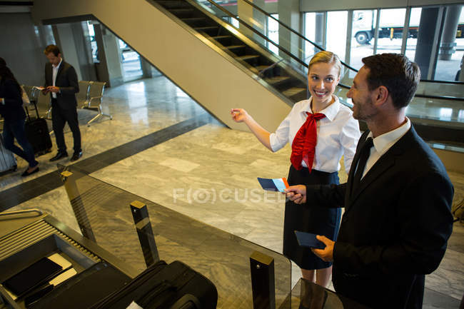 Mitarbeiterin zeigt Geschäftsmann am Flughafen-Terminal die Richtung — Stockfoto