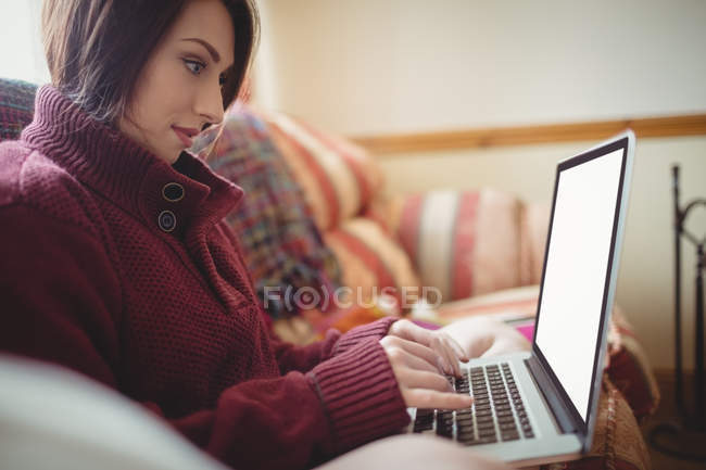 Красива жінка використовує ноутбук на дивані вдома — стокове фото
