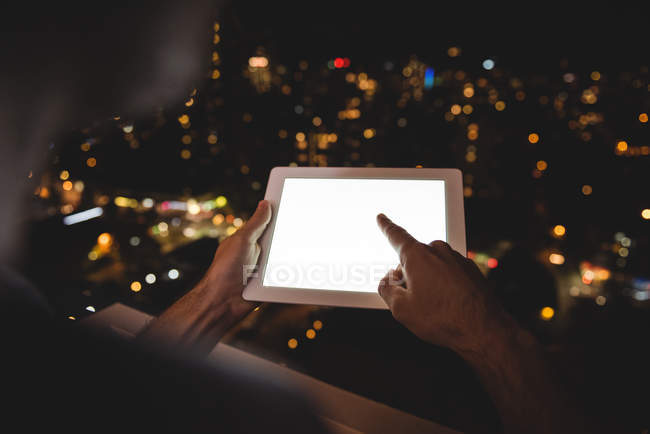 Крупним планом чоловік використовує цифровий планшет на балконі вночі — стокове фото