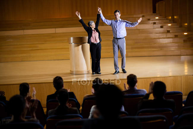 Female business executive appreciating a colleague on stage at conference center — Stock Photo