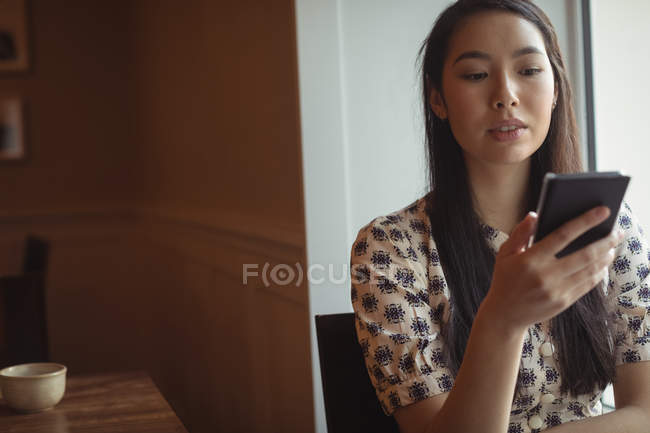 Woman using mobile phone near window at cafe — Stock Photo