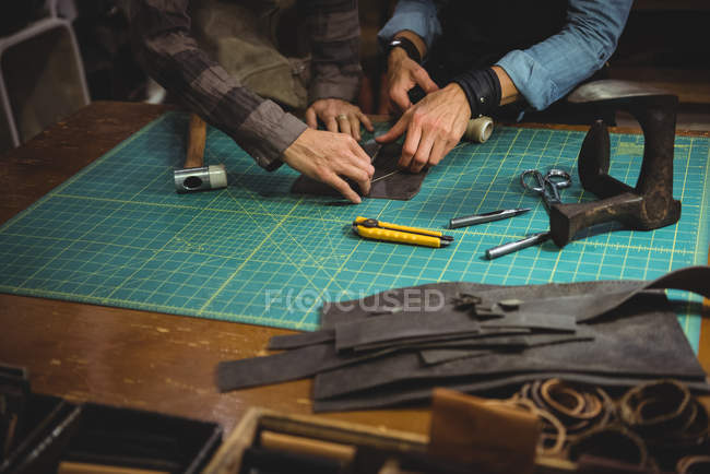 Artesãos discutindo sobre um pedaço de couro na oficina — Fotografia de Stock