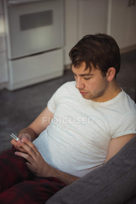 Крупним планом молодий чоловік використовує мобільний телефон на дивані вдома — стокове фото