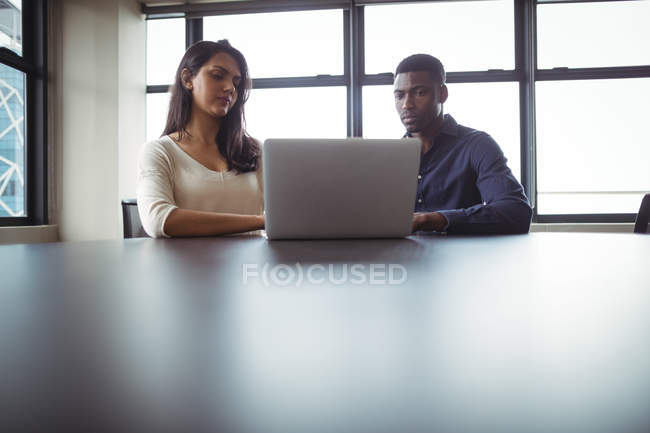 Бизнесмен и коллега работают за ноутбуком в офисе — стоковое фото