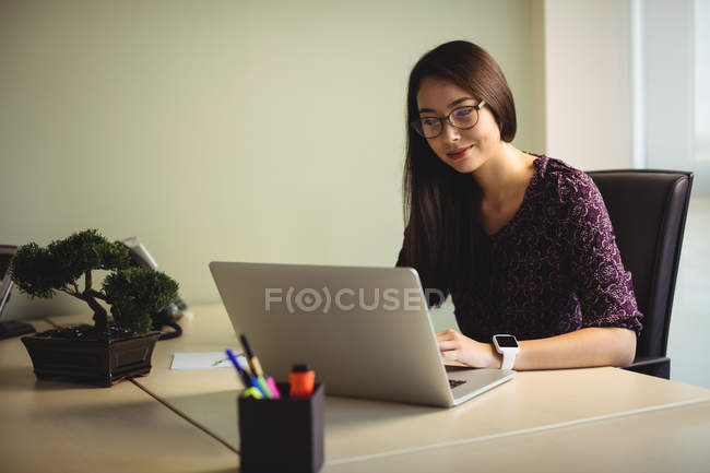 Бізнес-леді, що працює на ноутбуці в офісі — стокове фото