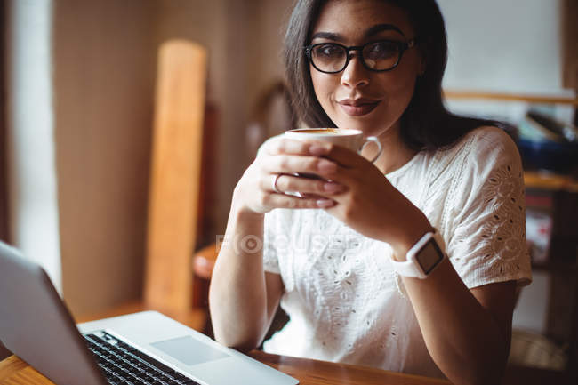 Retrato de una hermosa mujer tomando una taza de café en la cafetería - foto de stock
