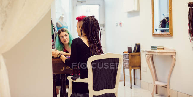 Proprietaria di un negozio femminile che interagisce con un cliente in un negozio di dreadlocks — Foto stock