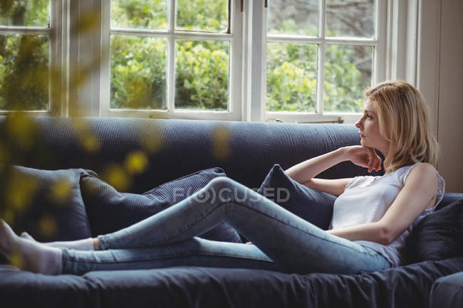 Mulher pensativo sentado no sofá na sala de estar em casa — Fotografia de Stock