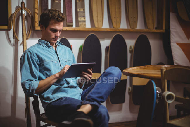 Человек с цифровым планшетом в магазине скейтбордов — стоковое фото