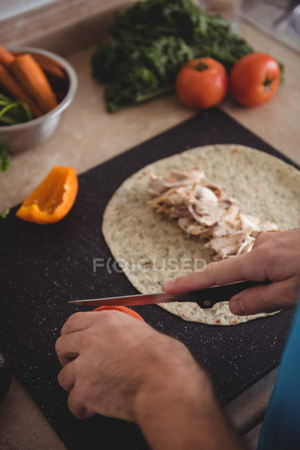 Hands of man slicing fresh tomato on cutting board in the kitchen at home — Stock Photo