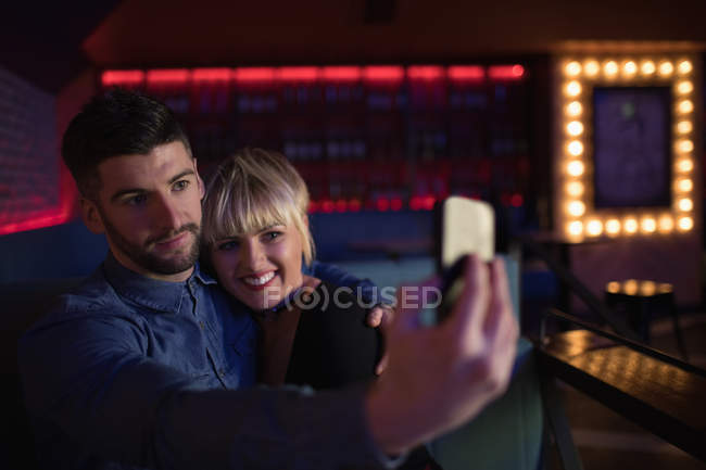 Sorrindo casal tirando selfie no celular no bar — Fotografia de Stock