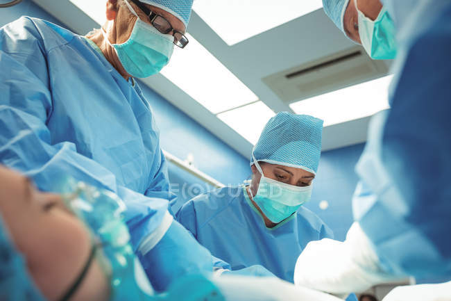 Equipe de cirurgiões que realizam operação em sala de operações no hospital — Fotografia de Stock