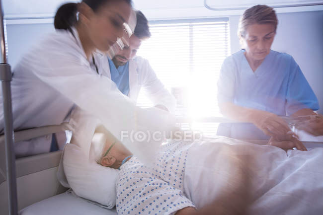 Team of doctors putting oxygen mask on a male senior patient face in the hospital — Stock Photo
