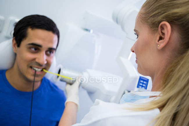 Dentista femenina tomando rayos X de dientes de paciente en la clínica - foto de stock