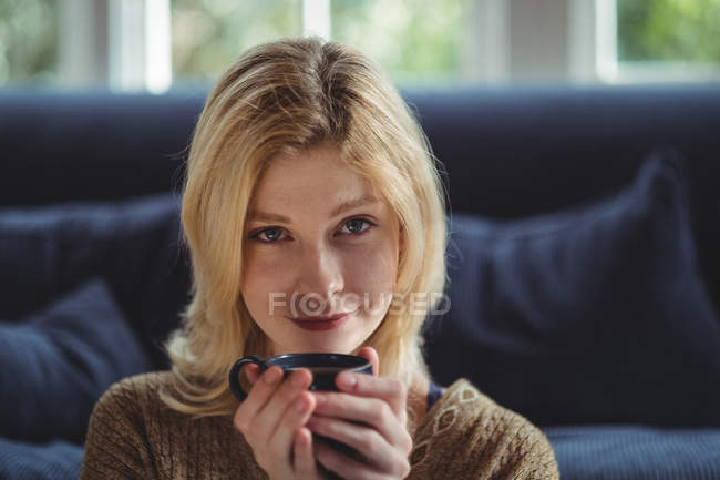 Portrait of beautiful woman having tea in living room at home — Stock Photo