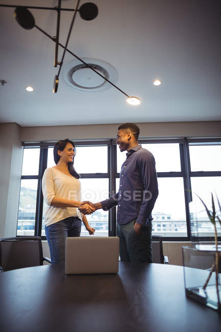 Businessman and a colleague shaking hands in office — Stock Photo