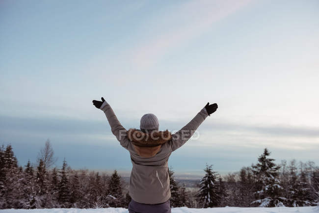 Donna in piedi con le braccia spalancate sul paesaggio innevato — Foto stock