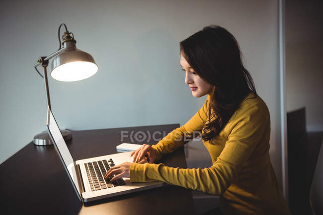 Femme travaillant sur ordinateur portable dans la salle d'étude à la maison — Photo de stock