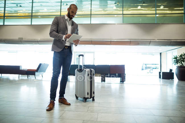 Бизнесмен, использующий цифровой планшет в зоне ожидания в терминале аэропорта — стоковое фото
