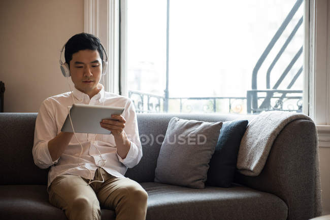 Man listening music on digital tablet at home — Stock Photo