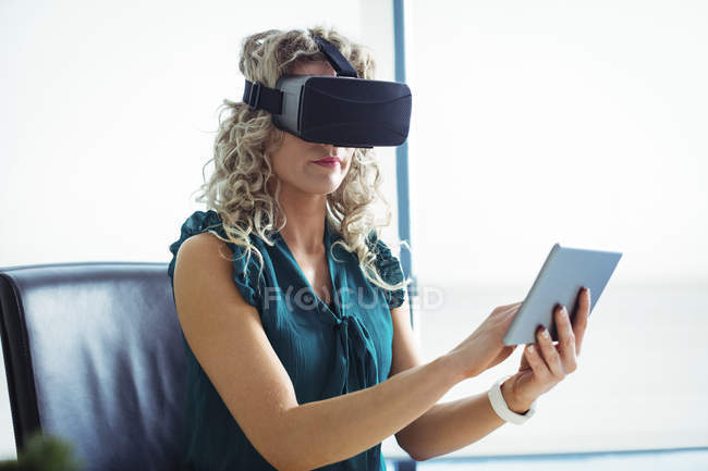 Бизнес-руководитель с помощью гарнитуры виртуальной реальности и цифрового планшета в офисе — стоковое фото
