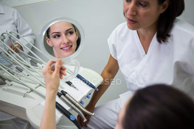 Paciente checando os dentes no espelho na clínica odontológica — Fotografia de Stock