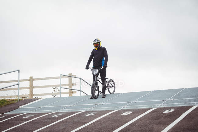 Cycliste debout avec BMX vélo à la rampe de départ dans skatepark — Photo de stock