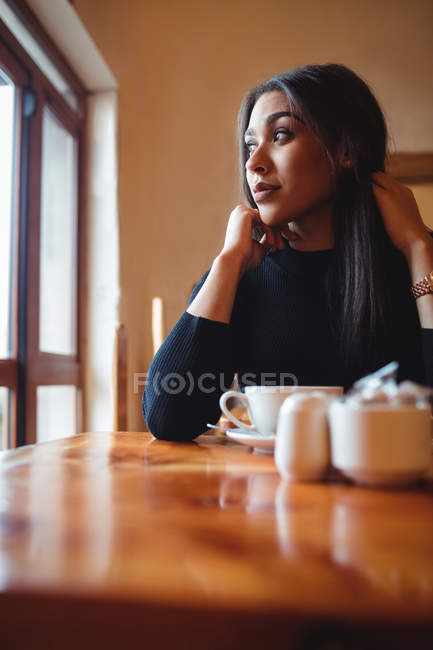 Femme réfléchie regardant par la fenêtre dans un café — Photo de stock