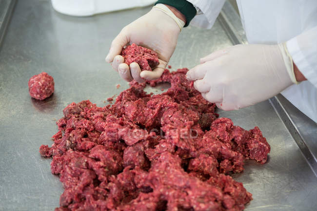 Sección media del carnicero preparando bolas de carne en la fábrica de carne - foto de stock