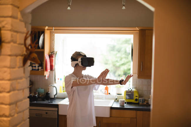 Frau gestikuliert mit Virtual-Reality-Headset zu Hause — Stockfoto