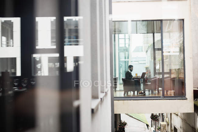 Man using laptop in bar interior, distant view — Stock Photo