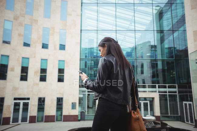 Жінка використовує мобільний телефон за межами офісних приміщень — стокове фото