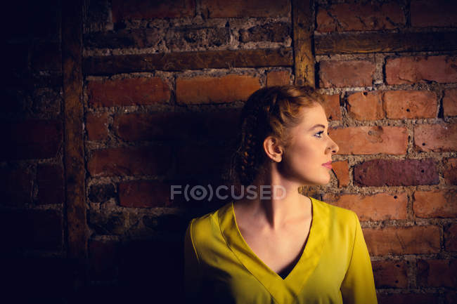 Beautiful woman standing against brick wall — Stock Photo