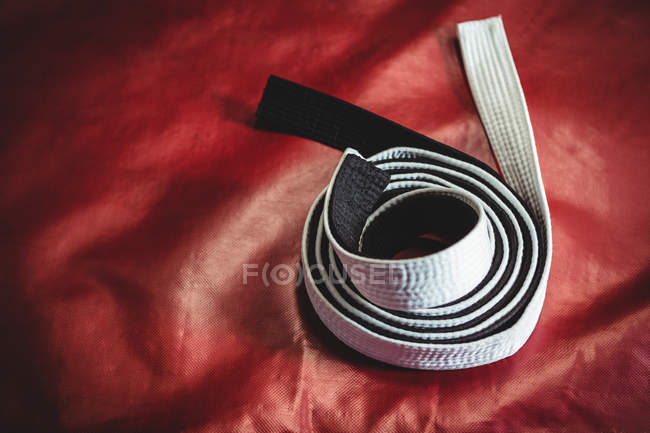 Cintura di karate laminato bianco e nero su sfondo rosso — Foto stock