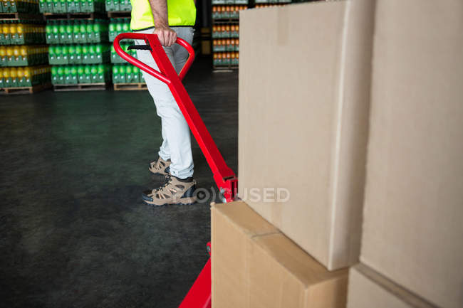 Low section of worker pulling trolley in warehouse — Stock Photo