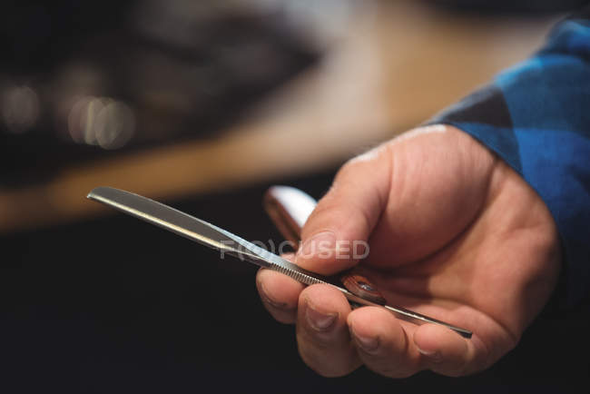 Close-up of barber hand holding razor in barber shop — Stock Photo