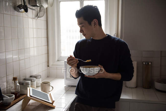Hombre usando tableta digital mientras desayuna en casa - foto de stock