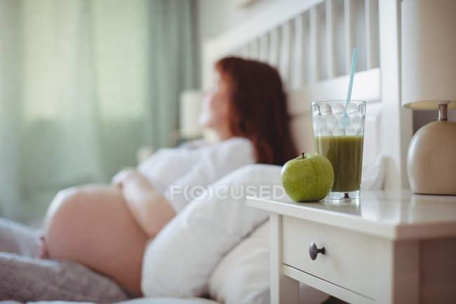 Juice and apple kept on table in bedroom at home — Stock Photo